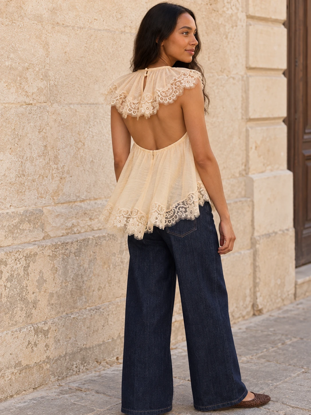 Rear three-quarter view of the Cream Ascent Flutter Top showing the deep open back, double button fastening at the nape and scalloped lace overlay
