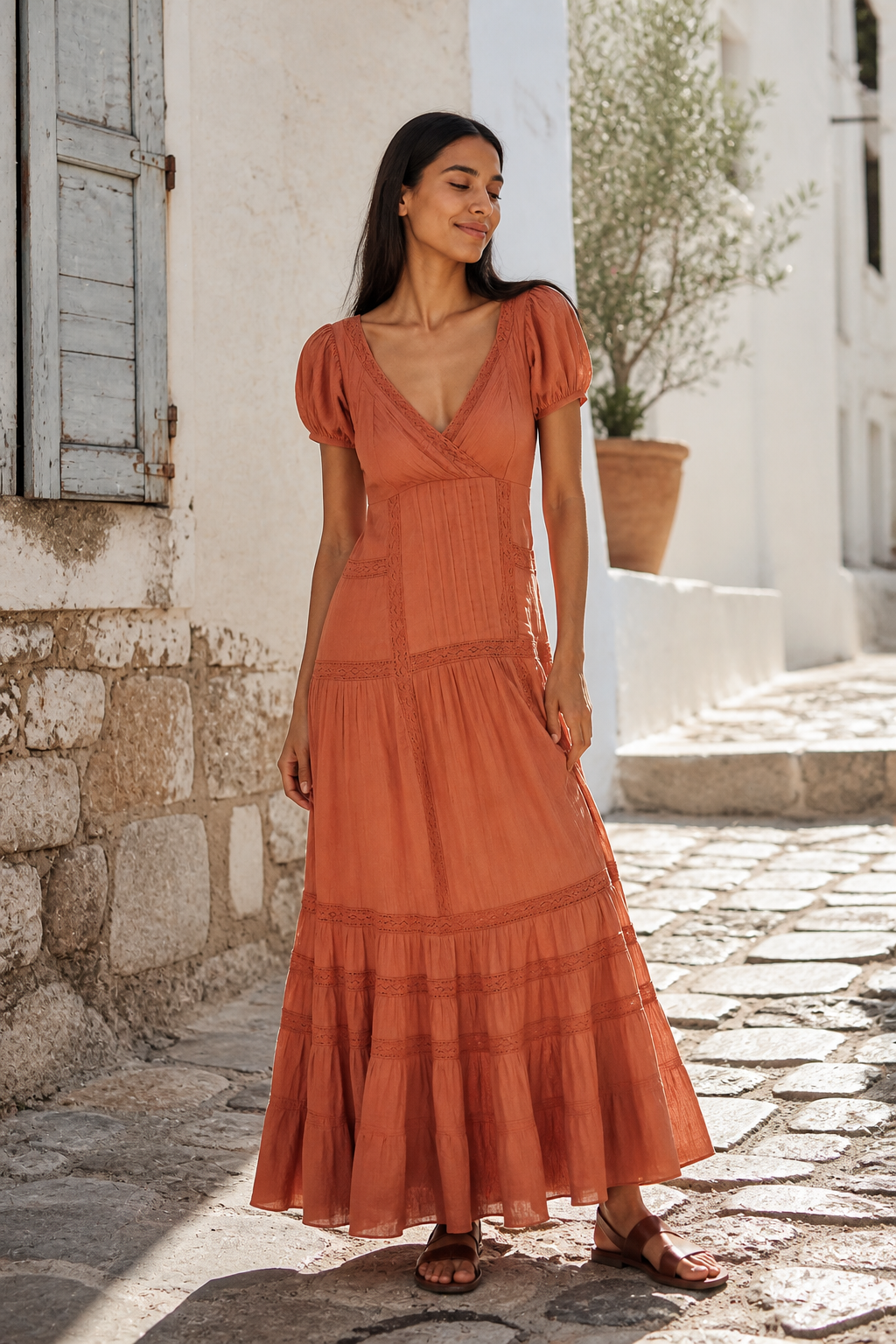 Full-body editorial photograph of Maya wearing the Free People Aura Maxi Dress in Honey Topaz, a warm terracotta maxi with V neckline, puff sleeves, pintucks, lace and a tiered skirt