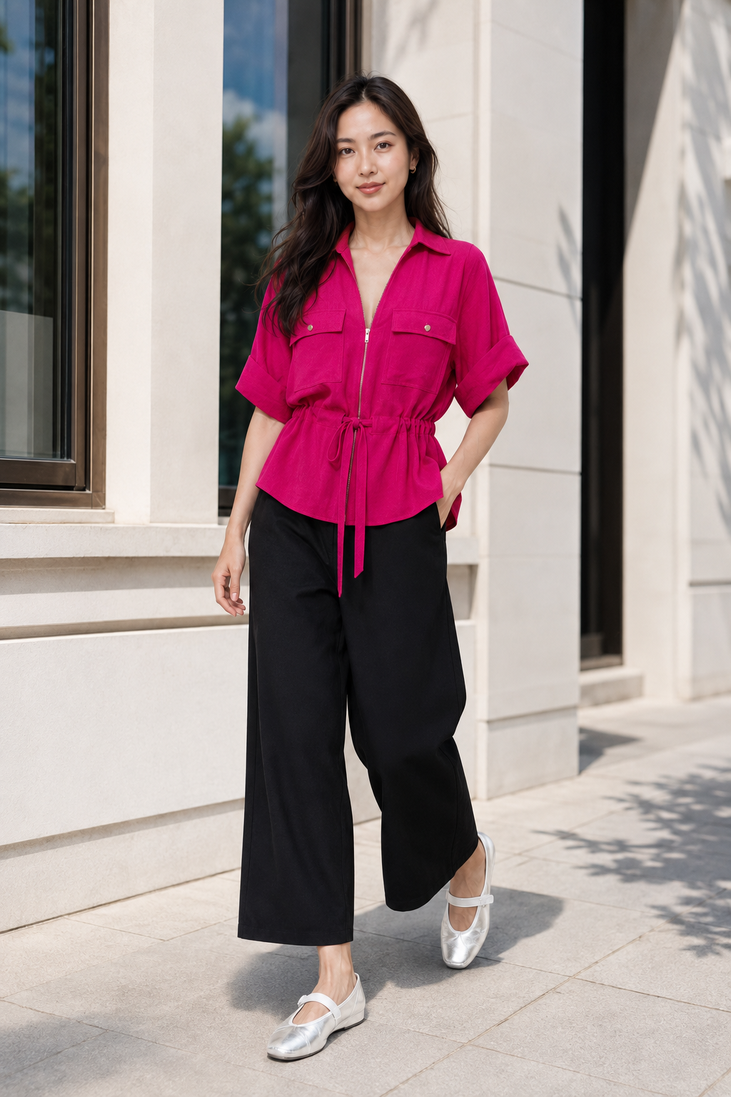 Full-body photograph of Hana wearing a Zara fuchsia safari shirt with tie belt, black wide-leg trousers and silver metallic leather sporty ballerinas